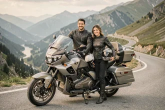 Couple de motards en veste de moto debout près d'une grande moto de tourisme sur une route de montagne panoramique