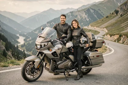Couple de motards en veste de moto debout près d'une grande moto de tourisme sur une route de montagne panoramique